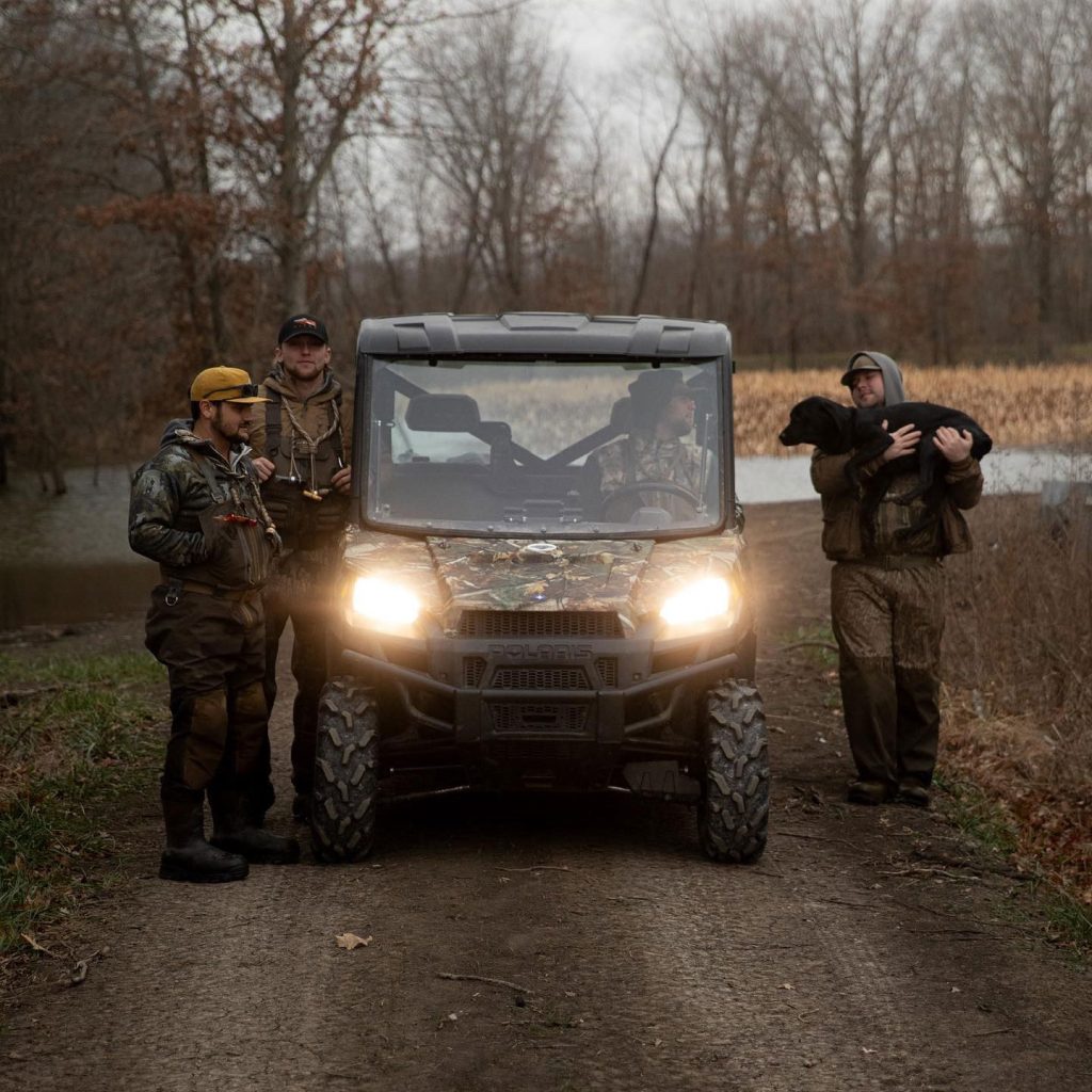 hunter and friends standing next to a polaris side by side